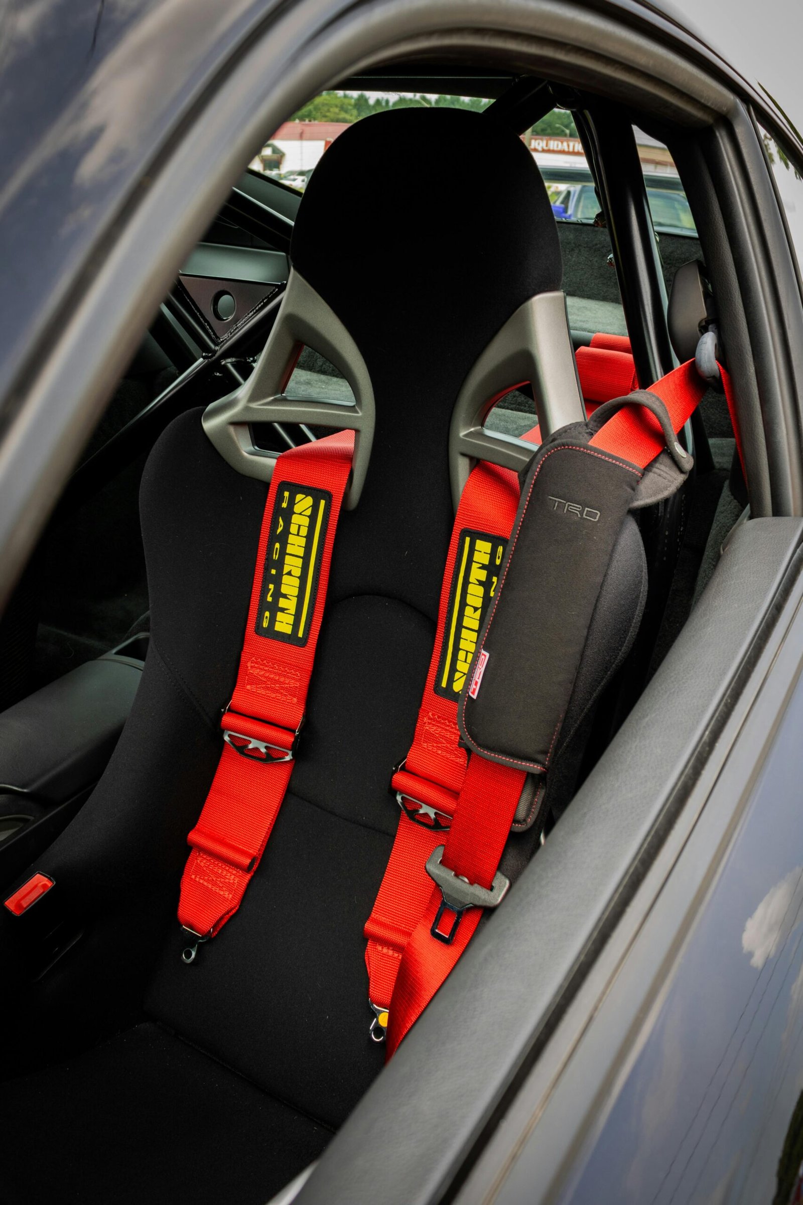 Car interior featuring a red racing harness seatbelt for enhanced safety.
